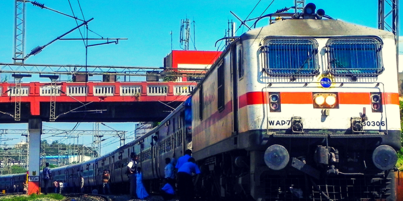 A Diesel Locomotive Hauling A Passenger Train Through A Railway Station In India.