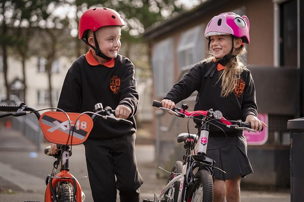 one boy and one girl, both school students are walking with their bicycles.